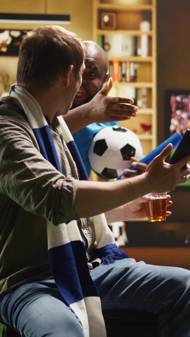 Video verticale: Primo piano di un tifoso di calcio a casa sul divano con lo smartphone in mano.