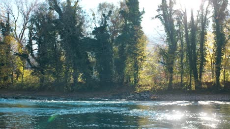 a serene river winds through a vibrant green landscape, kissed by the warm glow of the morning sun, with sunbeams filtering through the trees and creating dancing reflections on the water.
