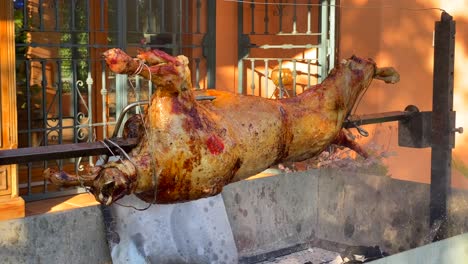 Asado-De-Cordero-Entero-Sobre-Un-Palo-Giratorio-De-Metal-Sobre-El-Fuego,-Piel-Dorada-Y-Crujiente,-Parrilla-De-Cordero,-Carne-Deliciosa,-Toma-Estática-De-4k