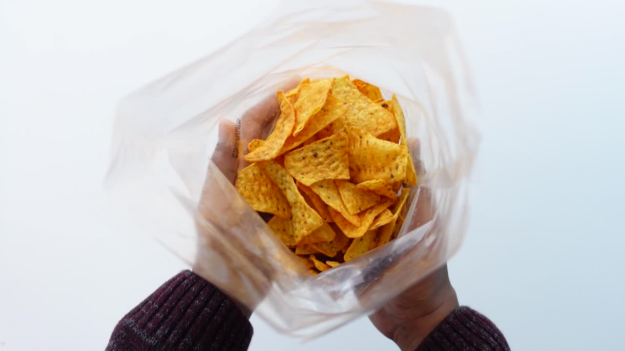 una mano sosteniendo una bolsa de papas fritas de tortilla