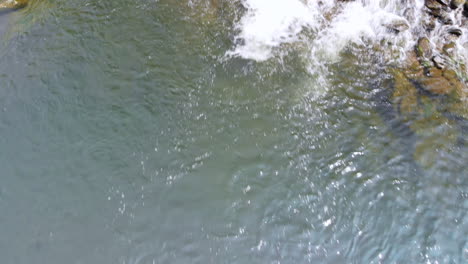 Aerial-close-up-slow-pan-of-a-small-creek-with-rapids,-23