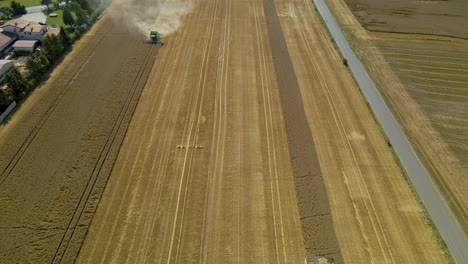 Traktoren,-Die-Während-Der-Erntesaison-In-Kielno,-Polen,-Auf-Dem-Goldenen-Feld-Arbeiten---Nach-Unten-Kippender-Pullback-drohnenschuss