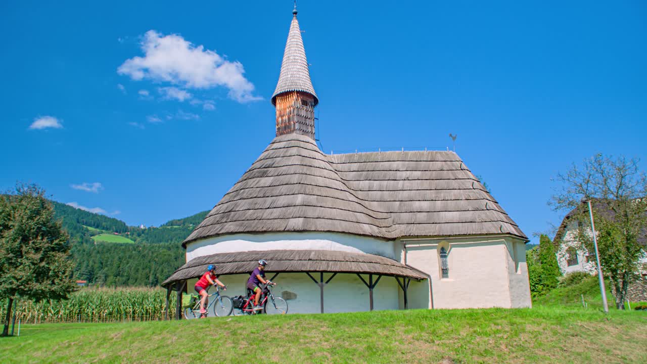 Two bikers admiring the Romanesque church St John the Baptist on a blue sky day