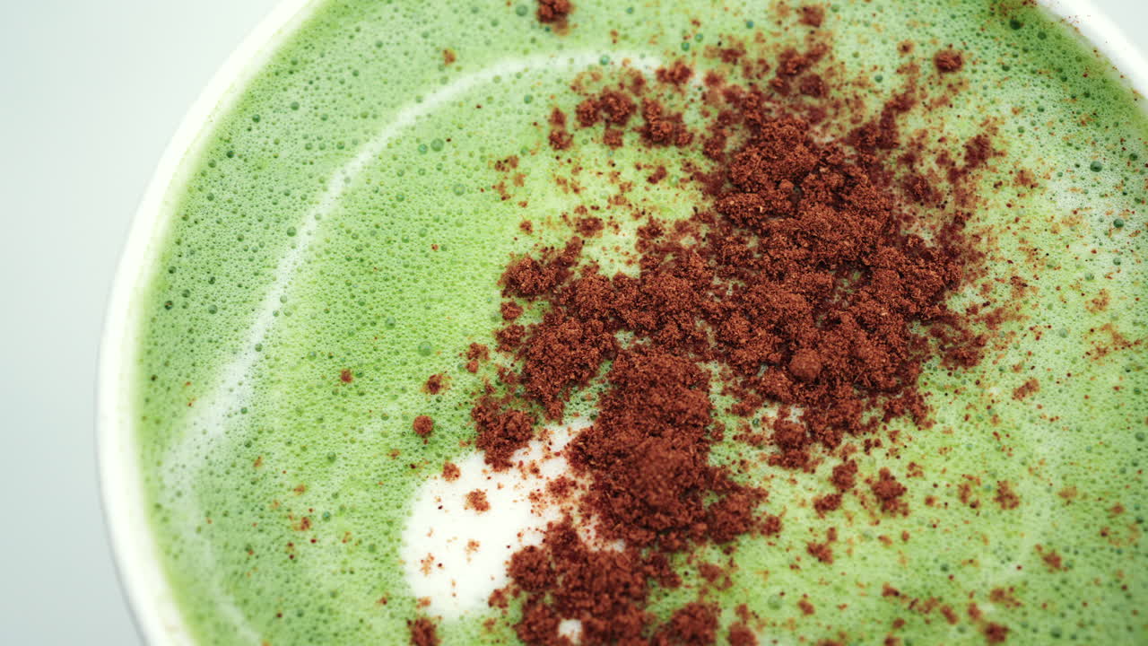 Primo piano di un cremoso latte matcha verde guarnito con polvere di cacao