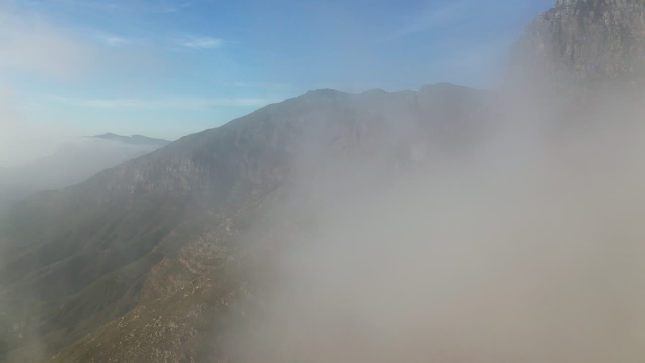 Aerial of Steep Jagged Mountain Landscape in Cape Town, South Africa. Drone shot backs up into big cloud.