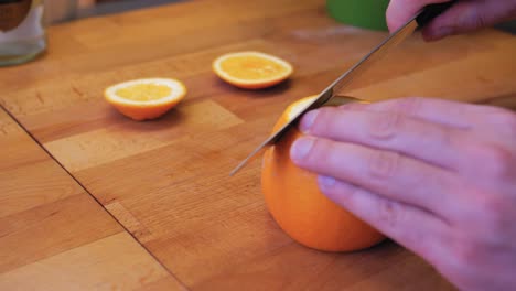 The-cook-cuts-the-orange-on-a-wooden-board