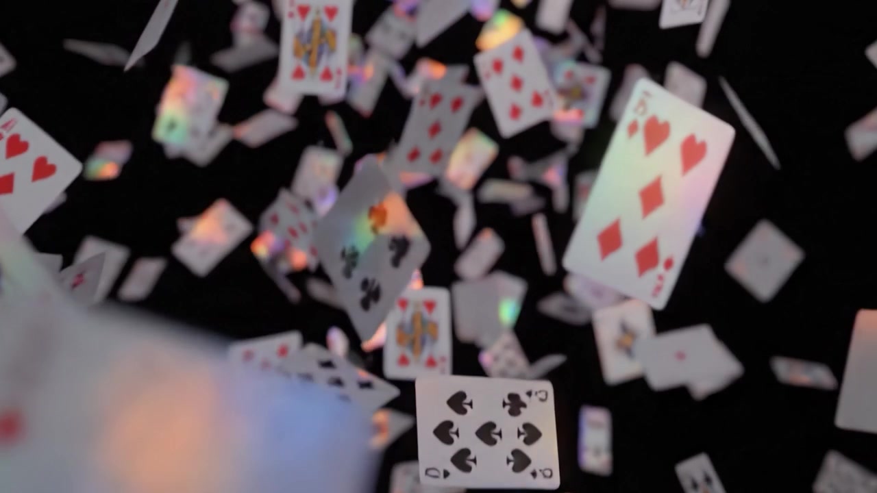Uno spettacolo mozzafiato di carte da gioco che cadono con colori vivaci su uno sfondo nero, catturando l'essenza del caso e della strategia nei giochi di carte
