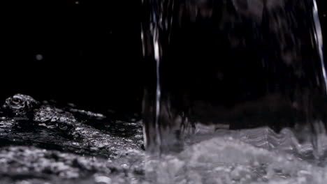 sheet of hot, steamy water pouring into black background waterfall filling up