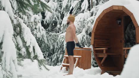 caucasian man warming up before winter swim in barrel.