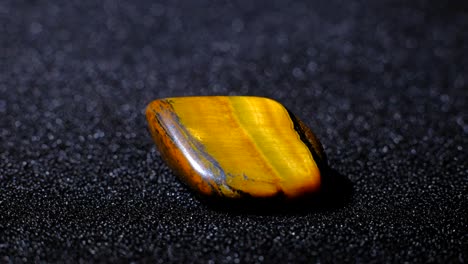 tiger's eye flat gemstone rotating on a black background