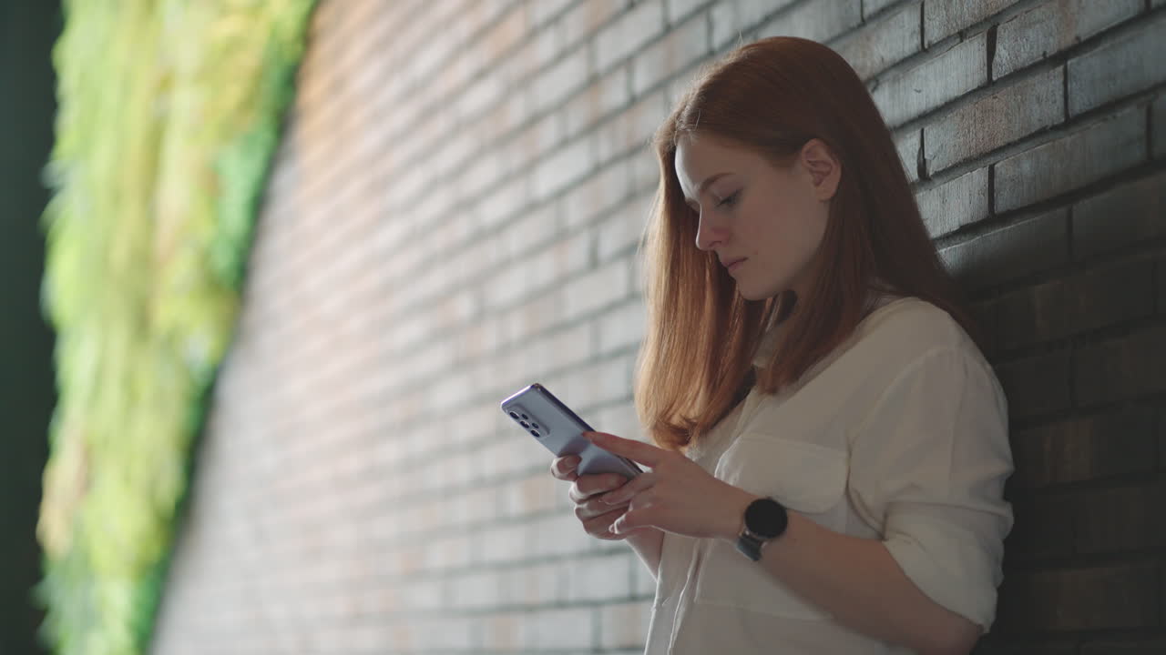 Smiling businesswoman using phone in office. Small business entrepreneur looking at her mobile phone and smiling. Woman texting in modern office