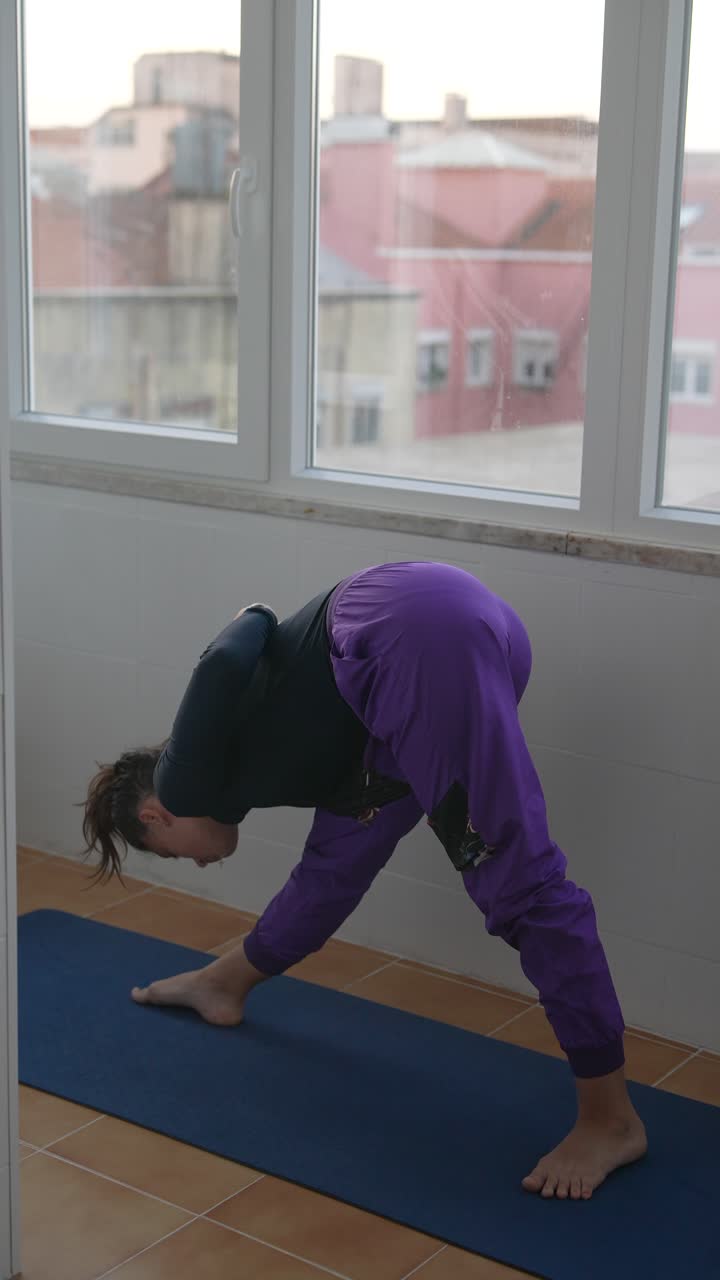 Donna che pratica posizioni yoga vicino a una finestra