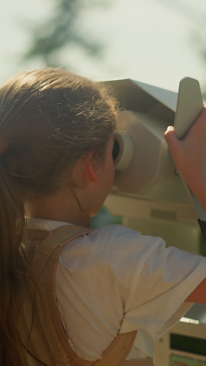 una chica curiosa explora el impresionante paisaje natural de la región montañosa a través de binoculares en un lugar turístico muy visitado en las vacaciones de verano. memoria de la infancia en cámara lenta