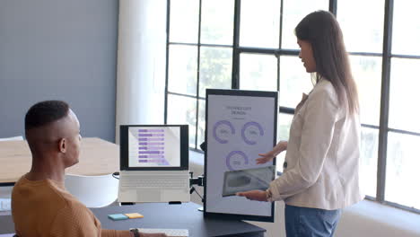 Presenting data on tablet, woman discussing technology design with colleague in office