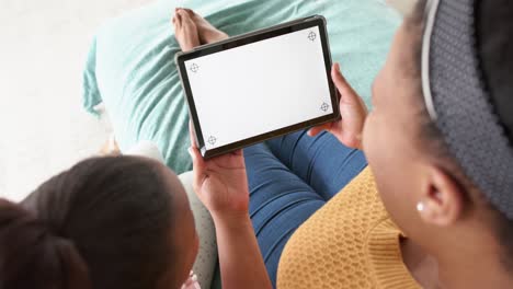 Happy-african-american-mother-and-daughter-on-sofa-using-tablet-with-copy-space,-slow-motion