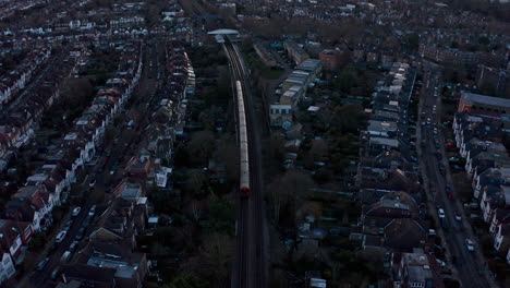Cinematic-rising-drone-shot-of-District-line-London-underground-train-into-Kew-Railway-station
