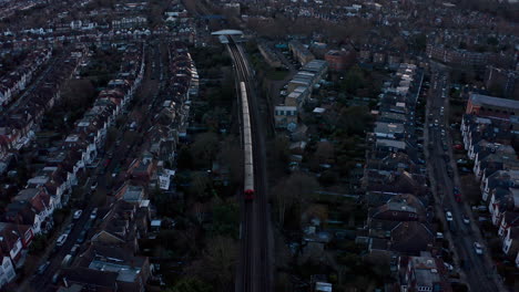 cinematic rising drone shot of district line london underground train into kew railway station