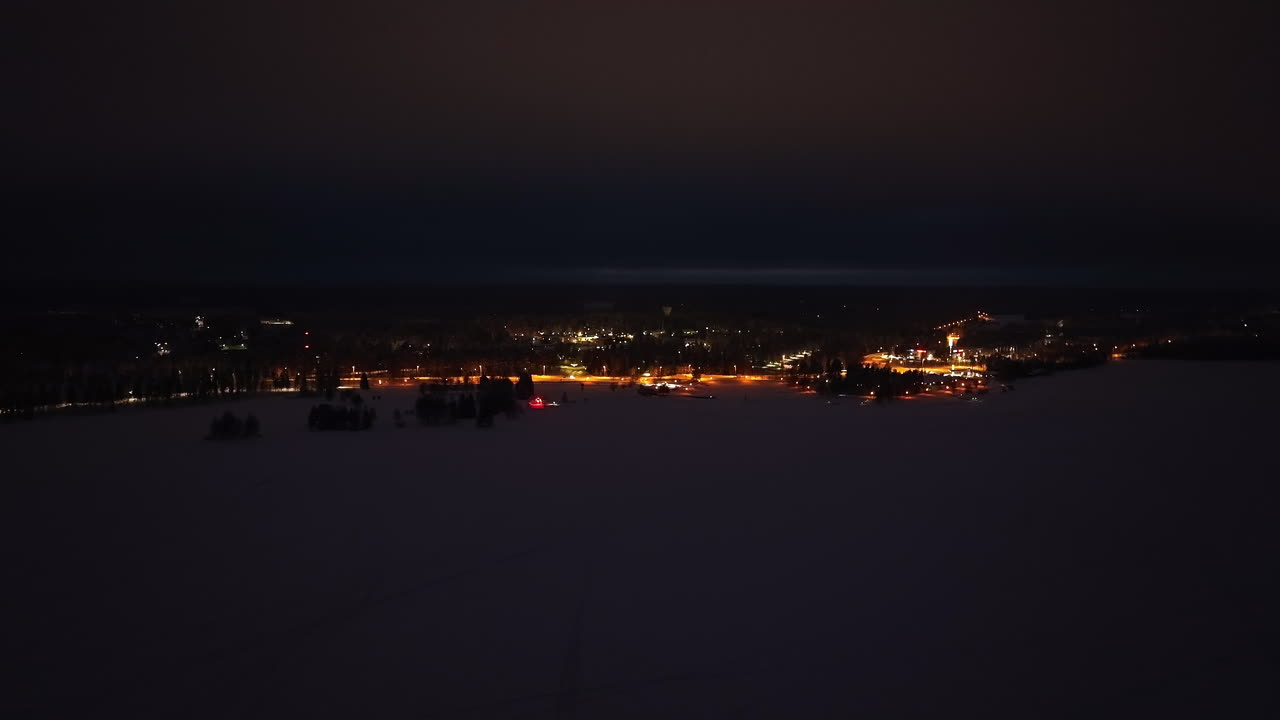 Aerial view flying sideways over ice, in front of the Suomussalmi town, in Finland