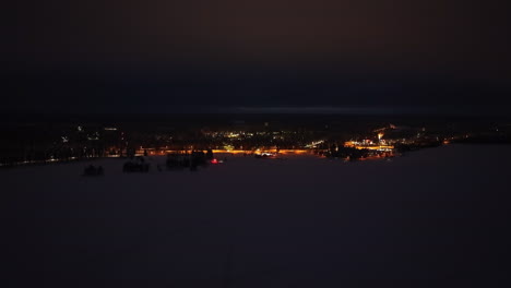 aerial view flying sideways over ice, in front of the suomussalmi town, in finland