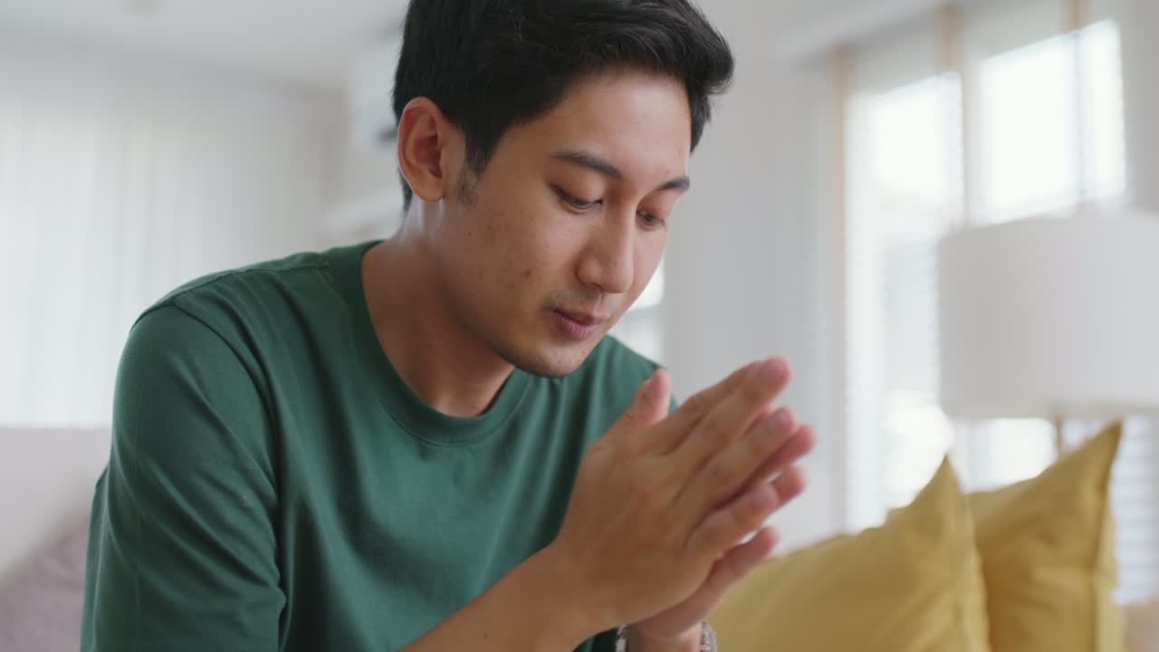 소파에 앉아 있는 아시아인 남자가 집에서 멀리 쳐다보며 생각나는 피로를 느다.