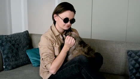 blind woman in sunglasses sitting on sofa at home and petting her cat 3