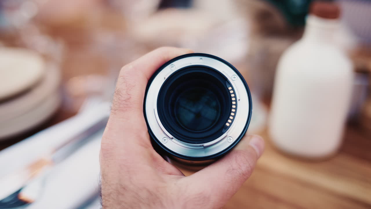 Primer plano de un objetivo de cámara sujetado en la mano con un bokeh de fondo suave