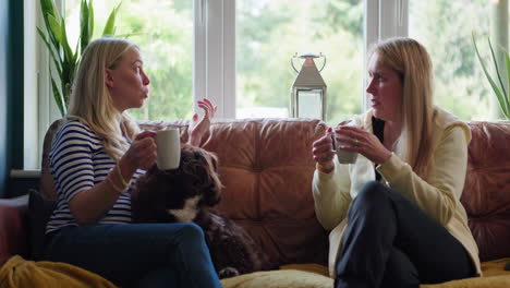 two women having a conversation with a dog on a couch