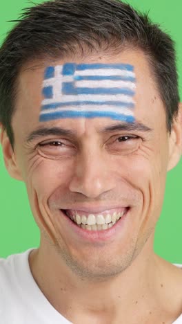 man with a greek flag painted on the face smiling