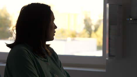 woman in hospital room looking out of window