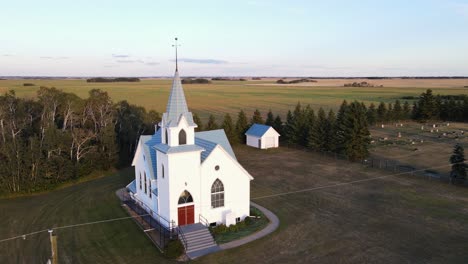 an ancient white church with a blue roof standing isolated in canada's rural countryside