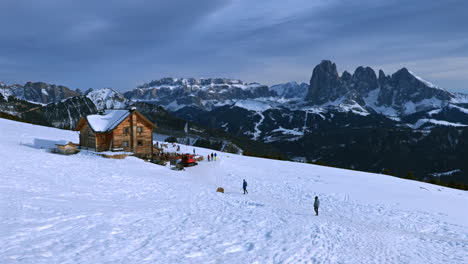 una acogedora cabaña de madera en un paisaje montañoso nevado con los impresionantes alpes dolomitas en el fondo