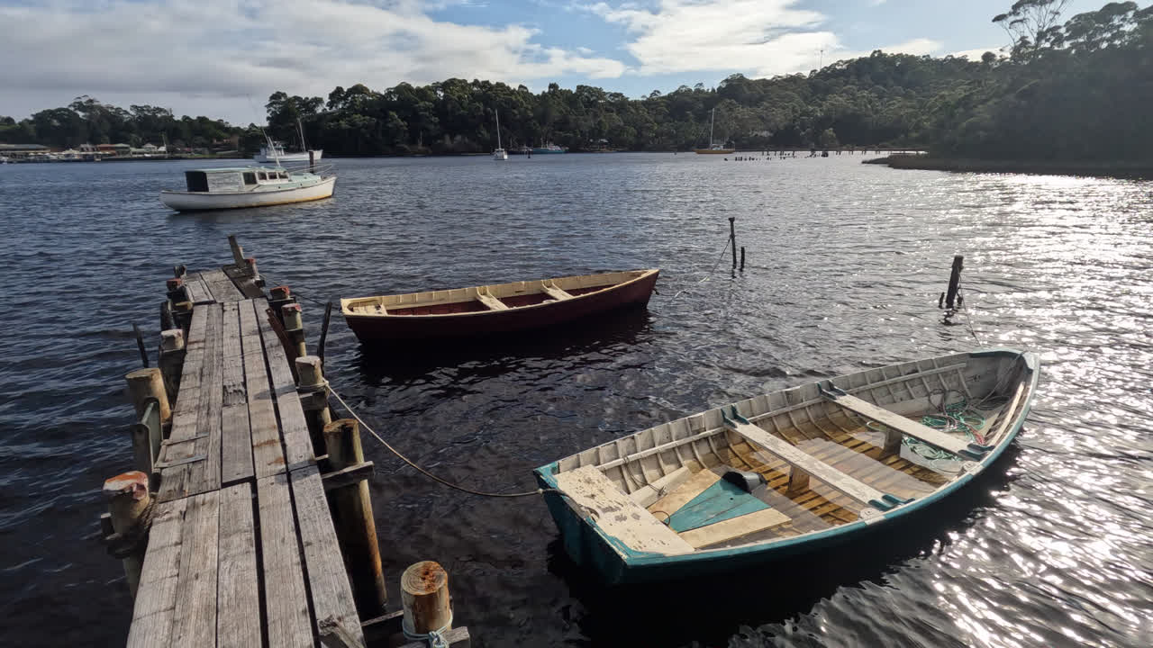 botes de remos flotando junto a un muelle de madera en strahan, costa oeste de tasmania