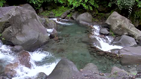 Pequeñas-Cascadas-Que-Entran-Y-Salen-De-Una-Piscina-Poco-Profunda-De-Agua-Clara-Y-Refrescante-De-Montaña-Con-Rocas-Y-Rocas-En-Una-Selva-Tropical