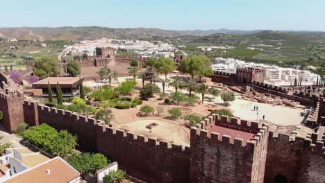 4k aerial drone footage circling the walls of the castle of silves and the beyond cityscape of the historical town of silves along the banks of the arade river in portugal