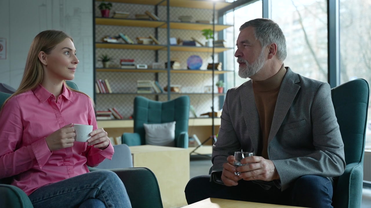 Mature Man and Young Woman Having a Conversation in a Modern Office