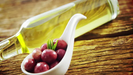 olive oil bottle and spoon full of red olives