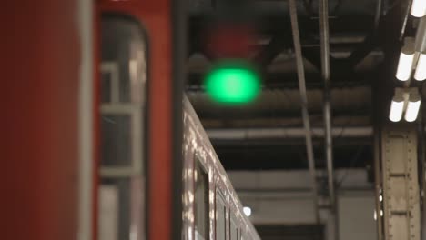 train at a station with red and green signal lights in focus, industrial setting