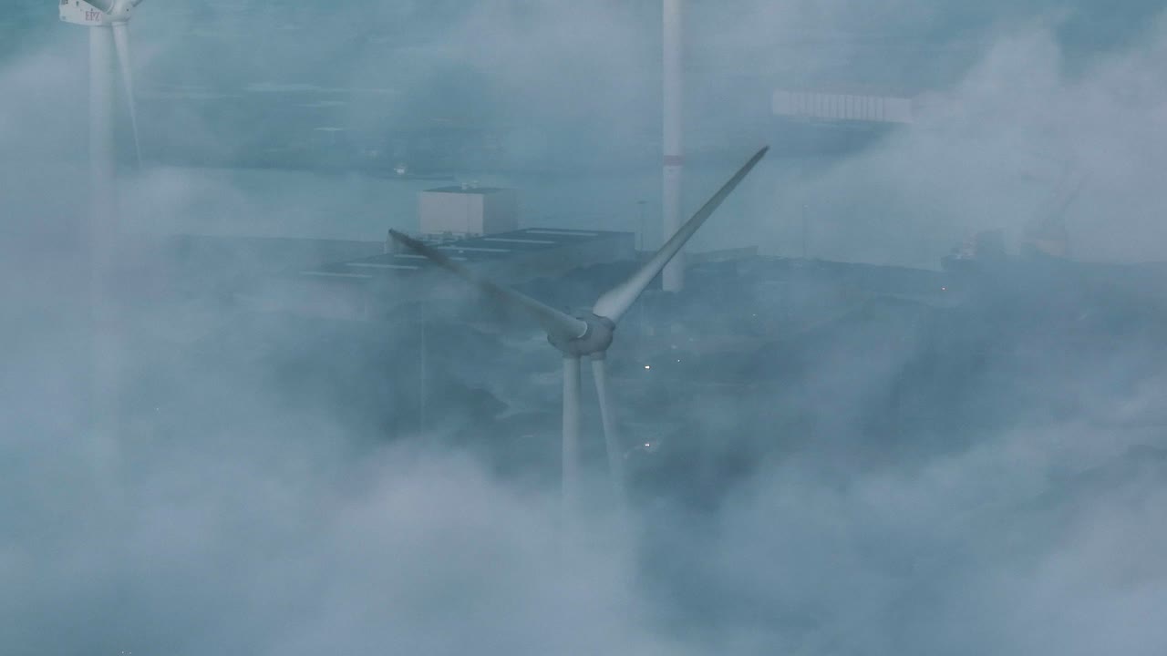 풍력 터빈의 블리싱겐 항구 위의 안개를 통해 촬영된 신비한 드론