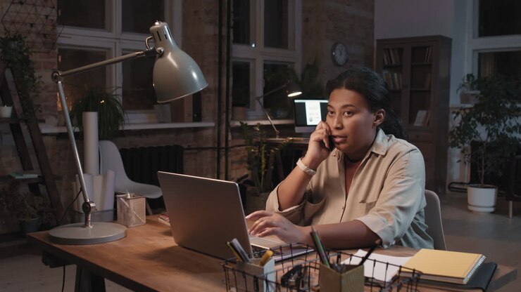 Woman working late on laptop and phone call in home office