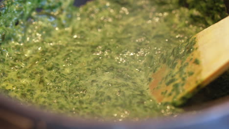 boiling spinach in a pan with a spatula