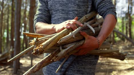 Mid-section-of-man-with-wooden-sticks-standing-in-the-forest-4k