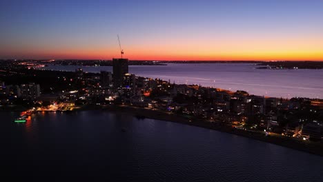 sun setting over the south perth skyline with lights glistening