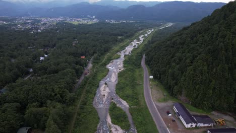 Village House Hakuba And Dense Forests Mountain Near Matsukawa River In Nagano, Kitaazumi District, Hakuba, Japan. Aerial Drone Shot