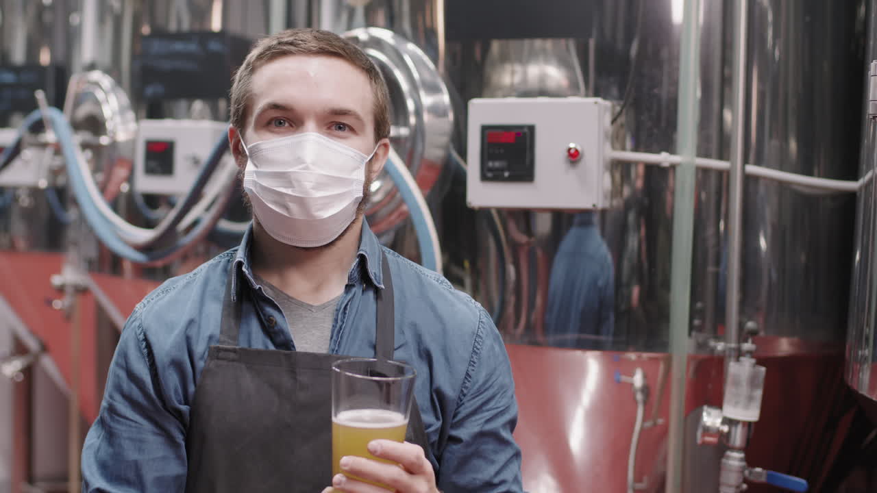 Brewery Worker In Mask With Glass Of Freshly Made Beer