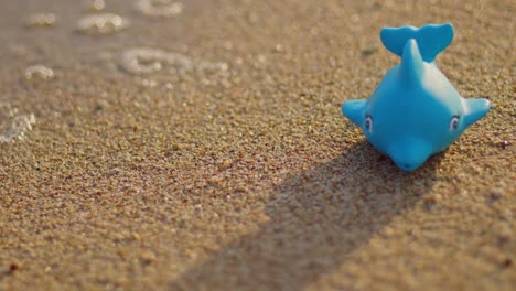 dolphin toy on sandy beach with sea waves