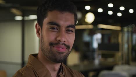 portrait of a mixed race businessman looking at camera and smiling in modern office