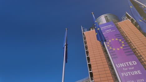 low-angle view of eu commission building with flags and banner