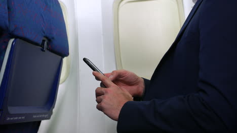 An-unrecognizable-nan-using-cell-phone-smartphone-on-plane-airliner-in-the-passenger-cabin-close-up