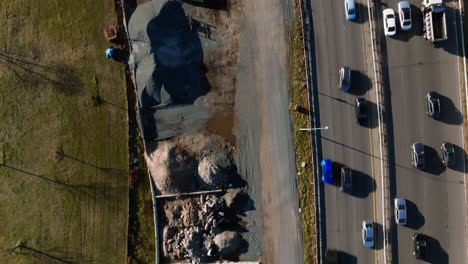 a top down view over a construction site with equipment and vehicles between the belt parkway and a park in brooklyn, ny on a sunny day