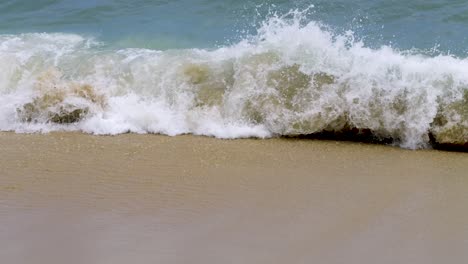close up view over waves breaking on tropical beach